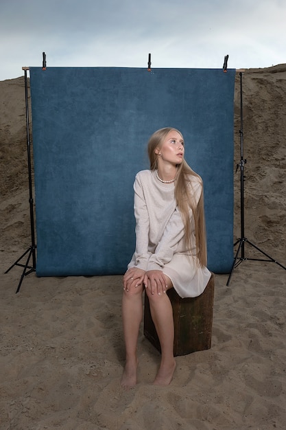 portrait à l'extérieur sur le sable devant fond bleu.