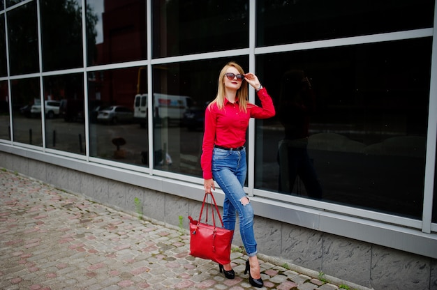 Portrait, fabuleux, jeune, femme, chemisier rouge, et, jeans, poser, elle, sac, et, lunettes soleil, dehors, les, centre commercial