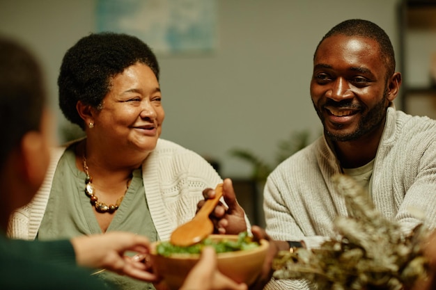 Portrait d'une famille afro-américaine heureuse discutant joyeusement tout en dînant ensemble