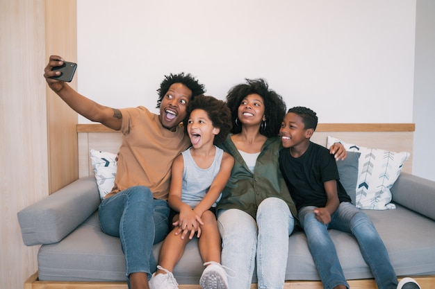 Portrait de famille afro-américaine prenant un selfie avec téléphone portable à la maison. Concept de famille et de style de vie.
