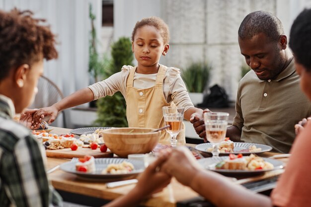 Portrait D'une Famille Afro-américaine Se Tenant La Main Au Dîner à L'extérieur Et Priant L'espace De Copie