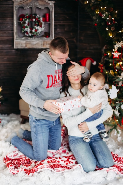 Portrait de famille aimante joyeuse déballant des cadeaux de Noël avec des enfants à la cheminée décorée et arbre de Noël