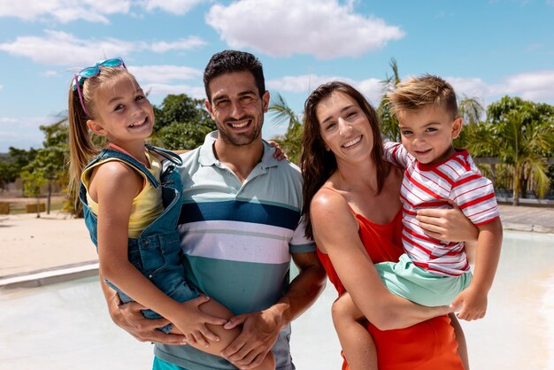 Photo portrait d'une famille biraciale heureuse embrassant au bord de la piscine. passer du temps de qualité, style de vie, famille, été et concept de vacances.