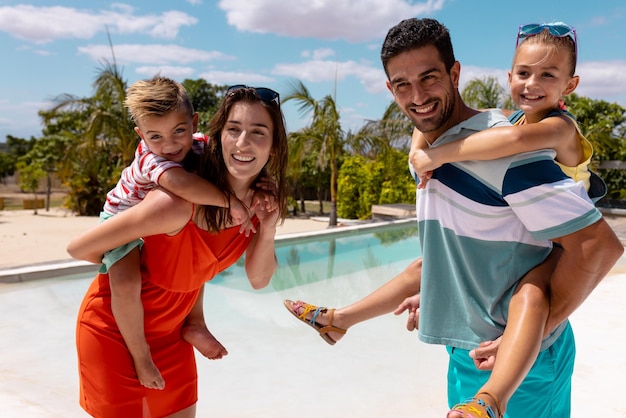 Portrait d'une famille biraciale heureuse souriant au bord de la piscine. Passer du temps de qualité, style de vie, famille, été et concept de vacances.