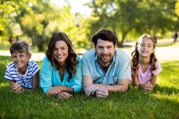 Portrait de famille heureuse allongé sur l'herbe dans le parc