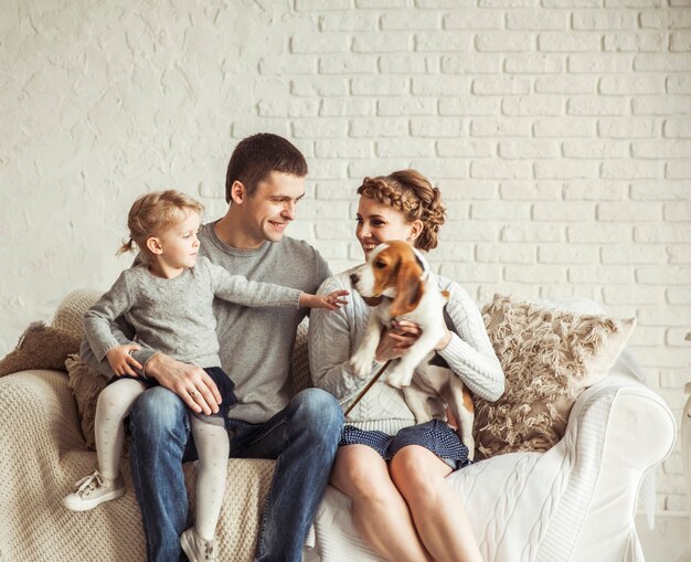 Portrait d'une famille heureuse et d'un animal assis sur un canapé