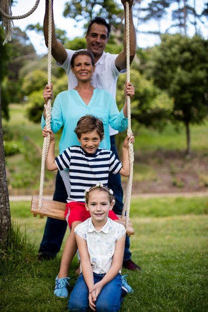 Portrait de famille heureuse assis sur une balançoire dans le parc