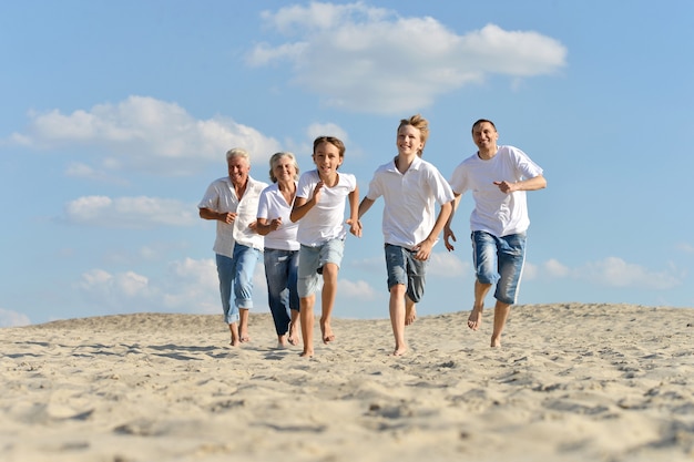 Portrait d'une famille heureuse courir pieds nus dans le sable en été