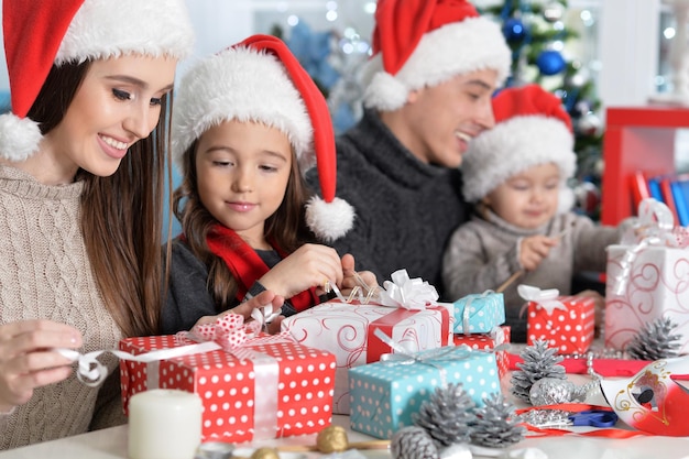 Portrait de famille heureuse dans des chapeaux de Santa se préparant pour Noël