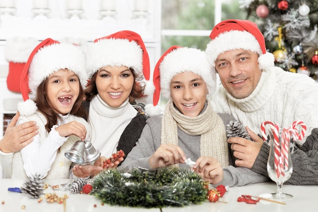 Portrait de famille heureuse dans des chapeaux de Santa se préparant pour Noël