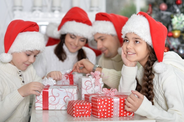 Portrait de famille heureuse dans des chapeaux de Santa se préparant pour Noël