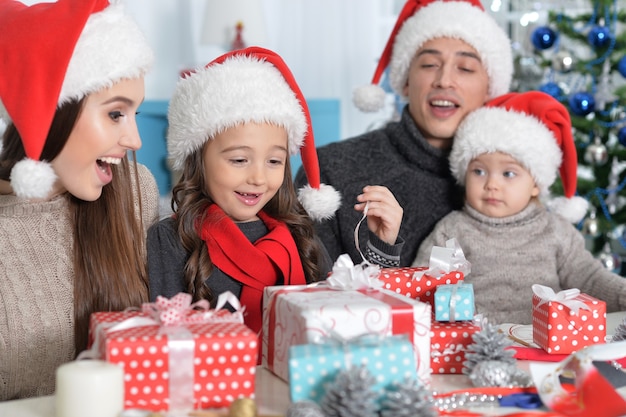 Portrait de famille heureuse dans des chapeaux de Santa se préparant pour Noël