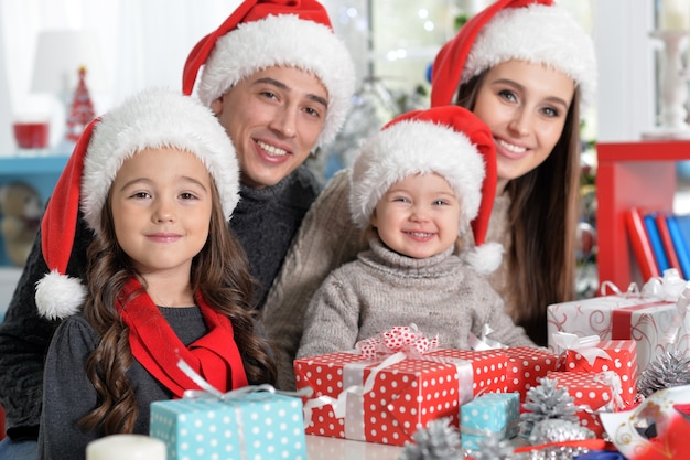 Portrait de famille heureuse dans des chapeaux de Santa se préparant pour Noël