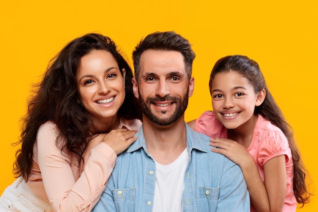 Portrait de famille heureuse sur un fond jaune de studio