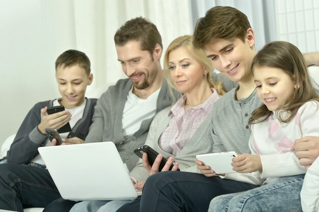 Portrait de famille heureuse avec des gadgets électroniques à la maison