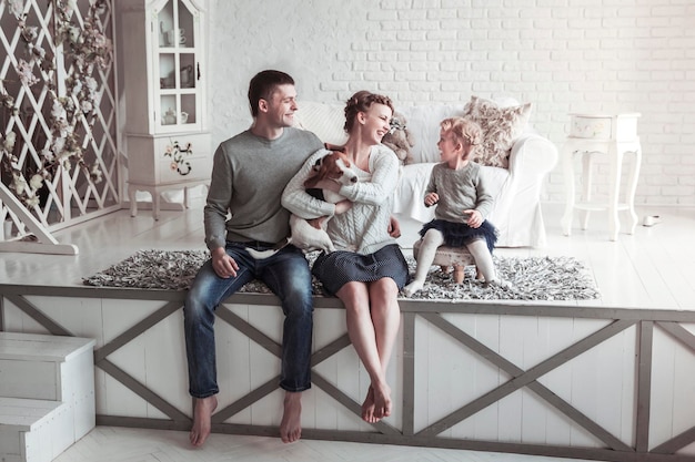 Portrait d'une famille heureuse et de leur animal de compagnie dans un salon confortable