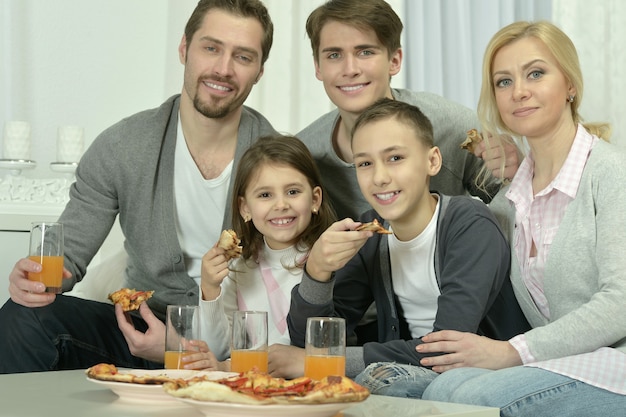 Portrait de famille heureuse à la maison avec pizza