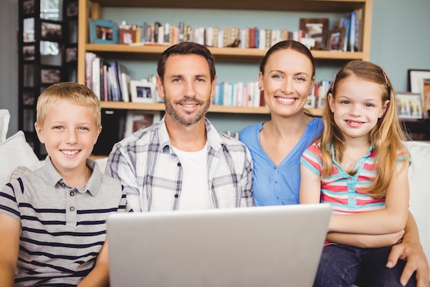 Portrait de famille heureuse avec ordinateur portable à la maison