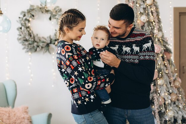 Portrait d'une famille heureuse de père mère et petit fils bouclé célébrant Noël ensemble à la maison Concept du Nouvel An