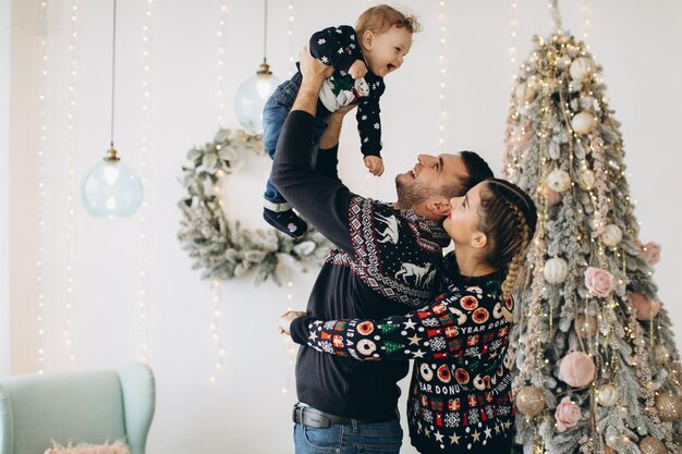 Portrait d'une famille heureuse de père mère et petit fils bouclé célébrant Noël ensemble à la maison Concept du Nouvel An