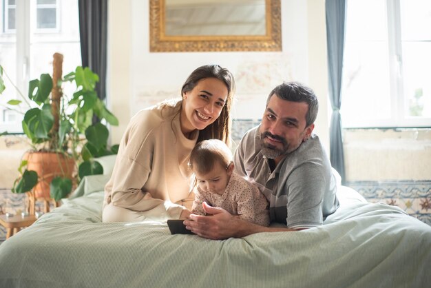 Portrait de famille heureuse avec petit enfant allongé sur le lit