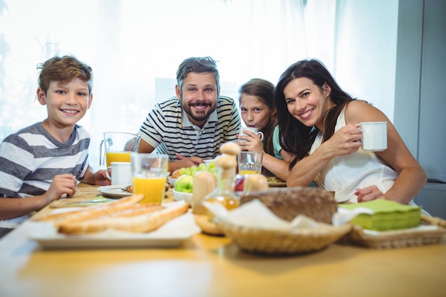 Portrait de famille heureuse prenant son petit déjeuner ensemble