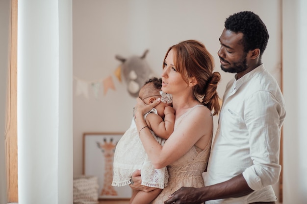 Portrait d'une famille interraciale heureuse et amicale avec un bébé basané ensemble dans la chambre des enfants