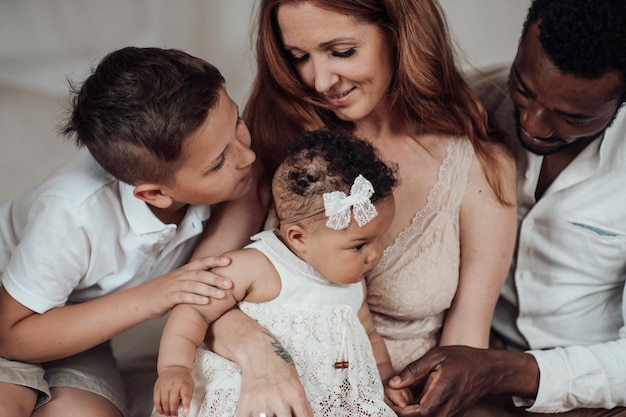 Portrait d'une famille interraciale heureuse et amicale avec deux enfants qui passent du temps ensemble à la maison