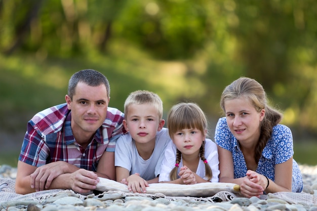 Portrait de famille de jeune mère heureuse, père et deux enfants blonds mignons, garçon et fille le jour d'été lumineux