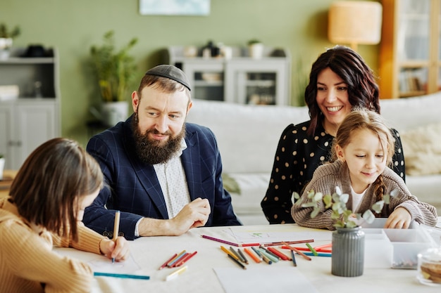 Portrait d'une famille juive moderne se rassemblant assis à table se concentrant sur le père souriant wea