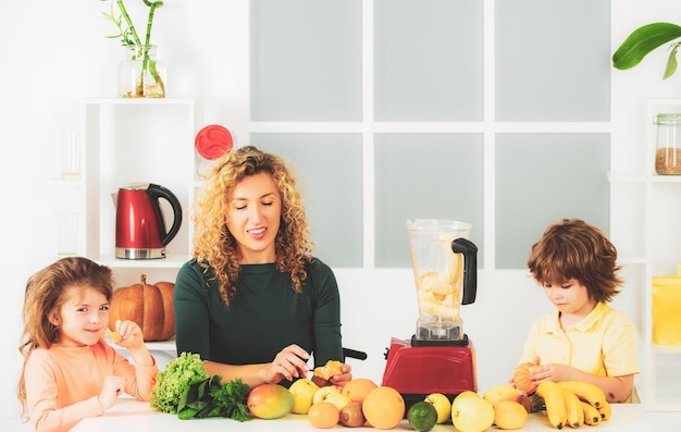 Le portrait de la famille mignonne fait le jus de fruit sur la cuisine blanche