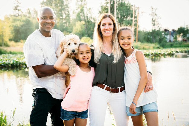 Photo portrait de famille mixte au bord du lac avec chiot labradoodle