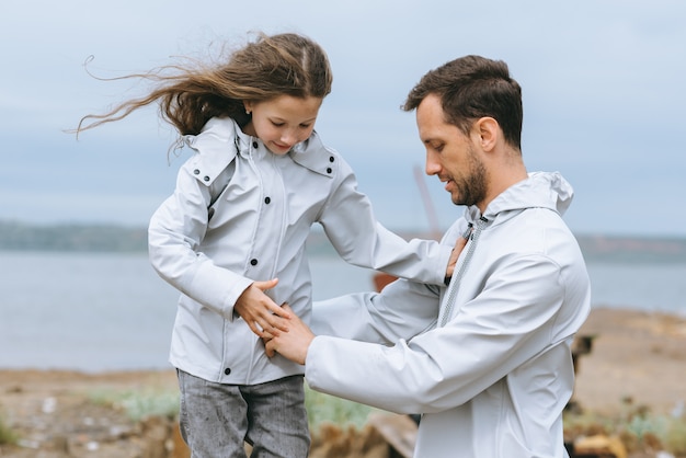 portrait de famille de papa et dauther en imperméable près de la mer