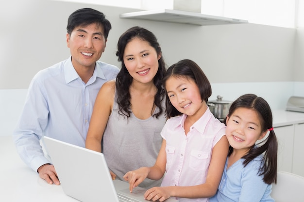 Portrait d&#39;une famille de quatre personnes avec ordinateur portable dans la cuisine