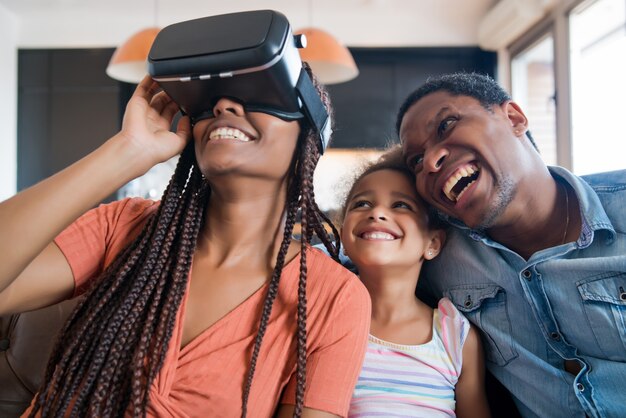 Portrait d'une famille s'amusant ensemble et jouant à des jeux vidéo avec des lunettes VR tout en restant à la maison.