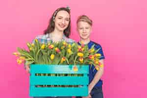 Photo portrait de famille sœur et frère adolescent avec des tulipes sur fond rose