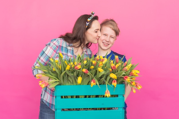 Portrait de famille sœur et frère adolescent avec des tulipes sur fond rose