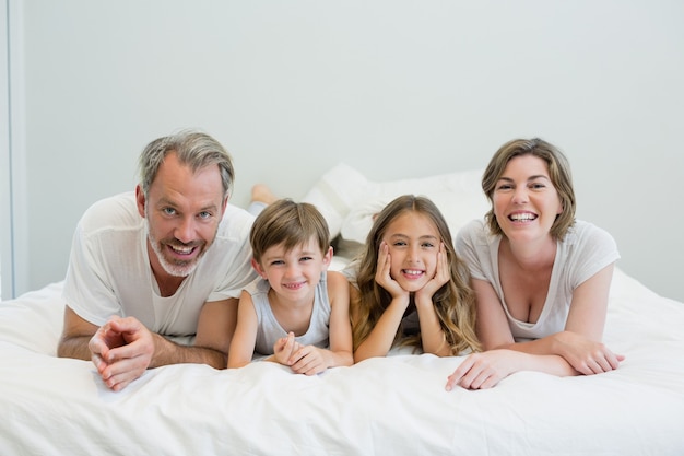 Portrait de famille souriante allongée sur le lit dans la chambre