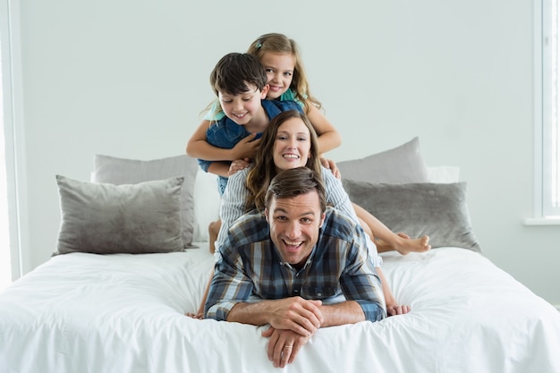 Portrait de famille souriante jouant sur le lit dans la chambre