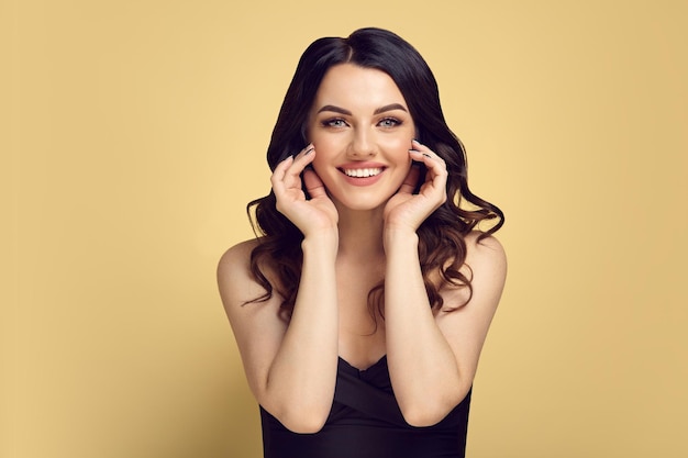 Portrait féminin baucasien d'une femme brune avec une peau propre et saine et des cheveux bouclés sur un jaune