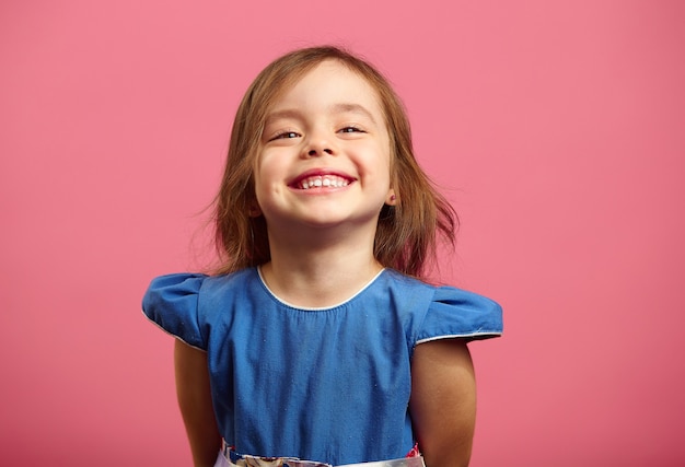 Portrait féminin d'un charmant enfant de trois ans avec un beau sourire, joyeux tir sur rose isolé.