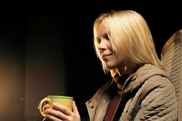 Portrait d'une femme de 42 ans aux cheveux blonds avec une tasse de thé dans une lumière chaude