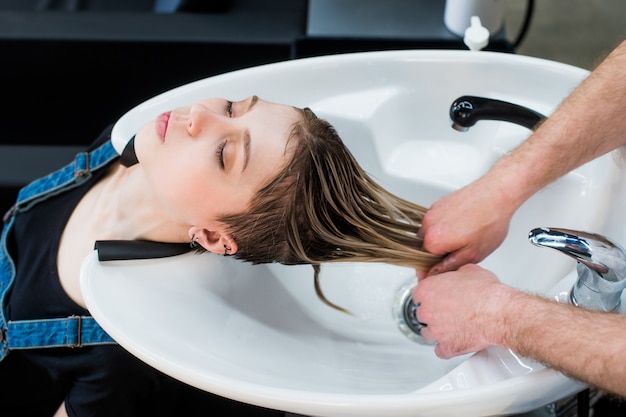 Photo portrait de femme adolescente cliente se laver les cheveux au salon de beauté. vue de dessus.