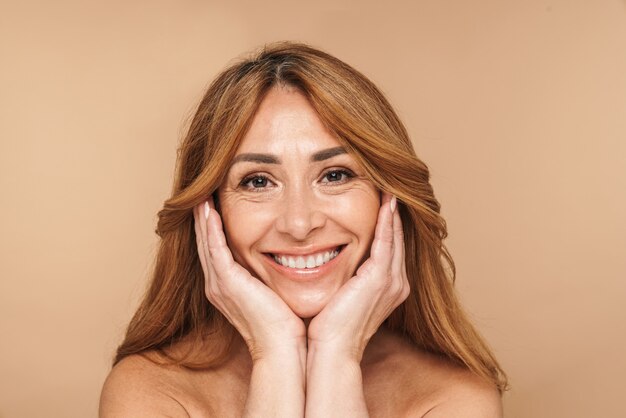 Portrait de femme adulte joyeuse souriante isolée sur beige