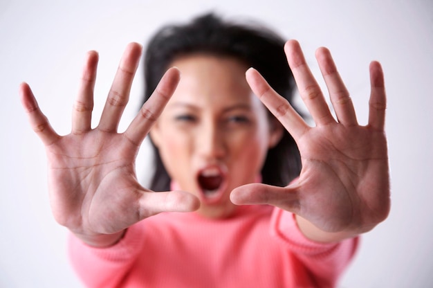 Photo portrait d'une femme adulte montrant un geste d'arrêt sur un fond blanc