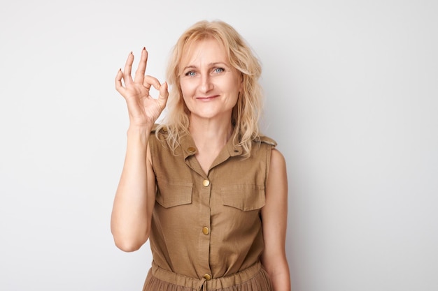 Portrait d'une femme adulte montrant le signe OK avec les doigts isolés sur un fond blanc Concept de carrière réussie accepté