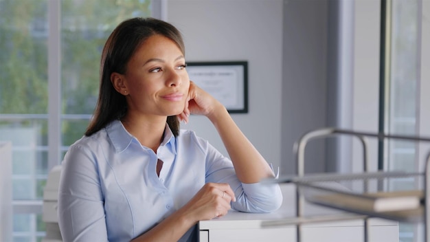 Portrait d'une femme d'affaires africaine pensive regardant par la fenêtre dans un bureau moderne