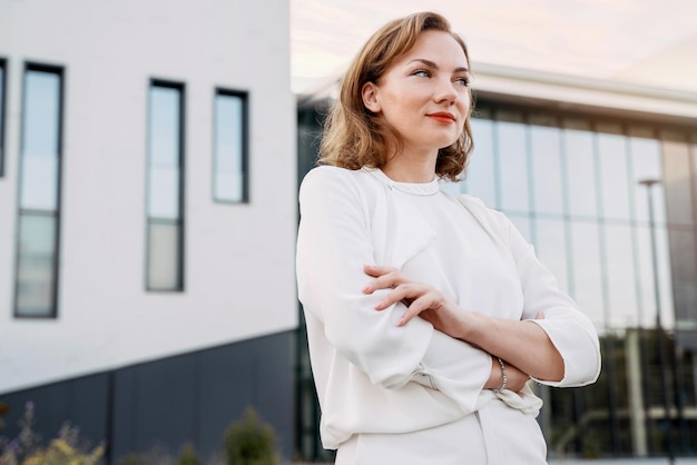 Portrait d'une femme d'affaires d'âge moyen confiante, les bras croisés, regardant loin dans la rue