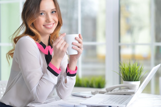 Portrait d'une femme d'affaires agréable avec un ordinateur portable au bureau