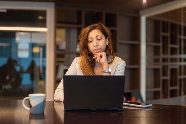 Portrait de femme d'affaires à l'aide d'un ordinateur portable la nuit au bureau